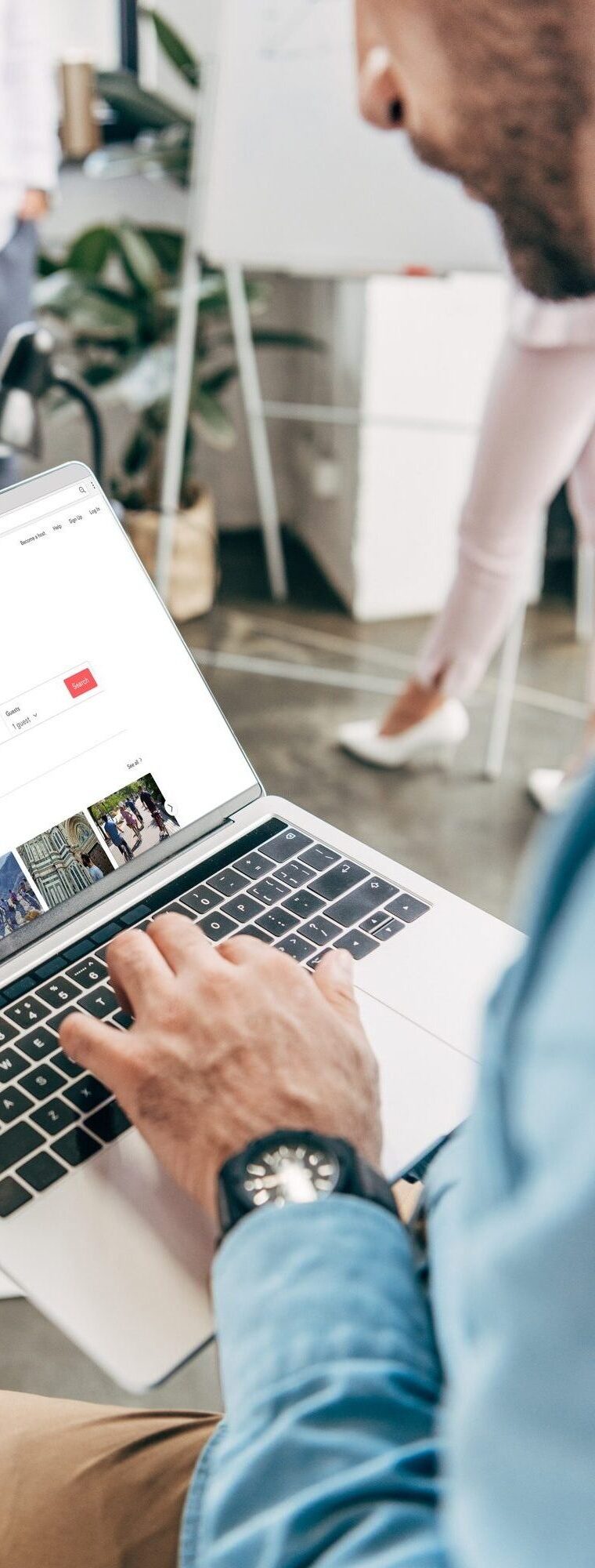 cropped shot of young businessman using laptop with airbnb website on screen
